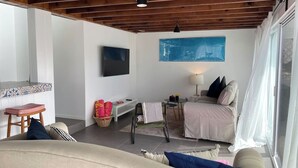 Un salon chaleureux avec un plafond en bois, un téléviseur à écran plat, un canapé, une petite table et un fauteuil.