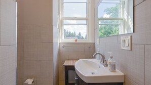 Un baño con ventana, lavamanos y espejo.