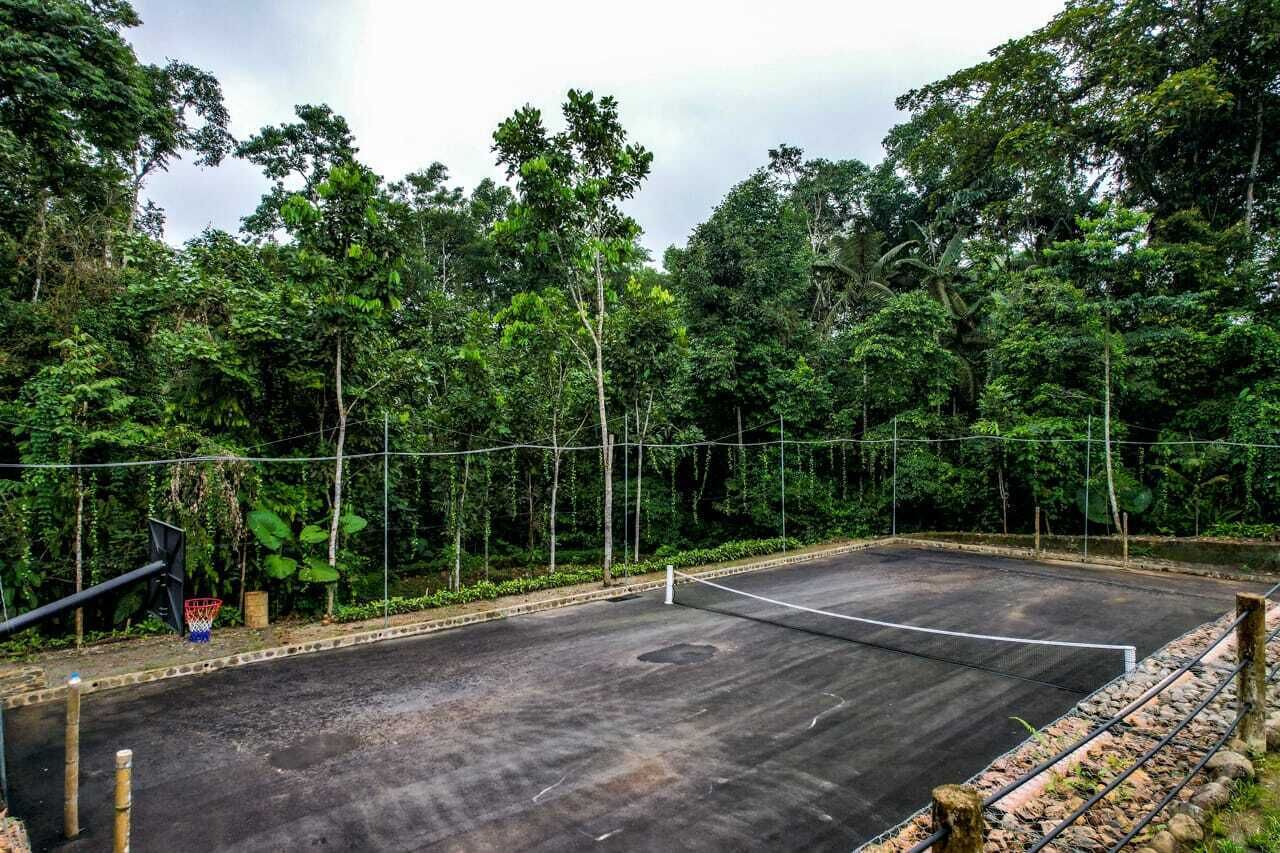 Una cancha de tenis al aire libre rodeada de un bosque denso.