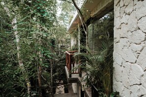 A lush indoor garden with a wooden staircase leading to a balcony. - Tulum Jungle Villa Agua (Tulum)