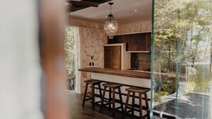 Eine moderne Küche mit Steinwand, Holzbarhocker und einer Pendelleuchte.