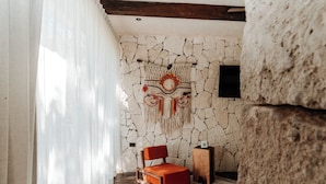 Une pièce avec un mur en pierre, une chaise rouge et un tapis à motifs.