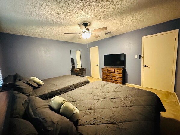A bedroom with a large bed, a ceiling fan, a dresser, a TV, and a door. - #3 Charming 4BR 2BA Home in Midland – Comfort, Convenience & Great Location! (Midland)