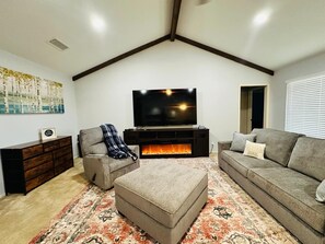 A living room with a fireplace, a television, a sofa, a chair, and a decorative rug. - #3 Charming 4BR 2BA Home in Midland – Comfort, Convenience & Great Location! (Midland)