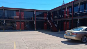 Un edificio de varios pisos con amplias ventanas y un área de estacionamiento.
