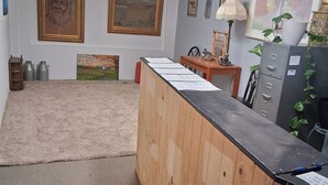 Una habitación con un mostrador de recepción de madera, un archivador y obras de arte en las paredes.