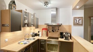 A modern kitchen with a wooden countertop, stainless steel appliances, and a red trash bin. - Alpenjuwel Oberstdorf – Mountain Views, Balcony & Sauna, Lift Pass, Dog Friendly (Oberstdorf)