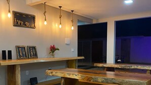 Un espace de restauration moderne avec des bancs et des tables en bois, des luminaires suspendus et des œuvres d’art murales.