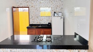 Une cuisine de taille réduite, équipée d’une cuisinière à gaz, d’un réfrigérateur blanc et d’un crédence décorée.