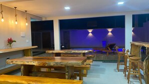 Un restaurant avec des tables et des bancs en bois, un coin bar et un espace détente aménagé au bord de la piscine.
