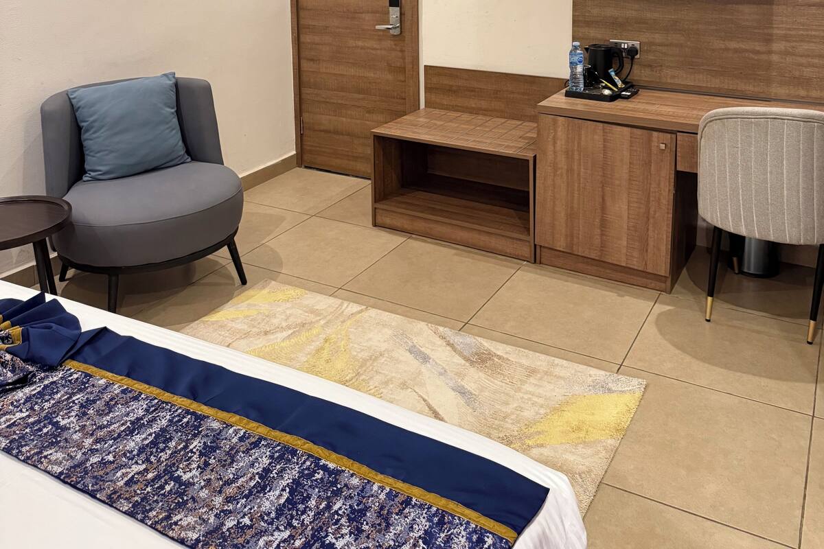 Een hotelkamer met een bed, een bureau, een stoel, een televisie en een deur met slot.