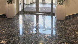 A hotel entrance with a glass door, marble flooring, and potted plants. - SAAFI Boutique Hotel (Abuja)