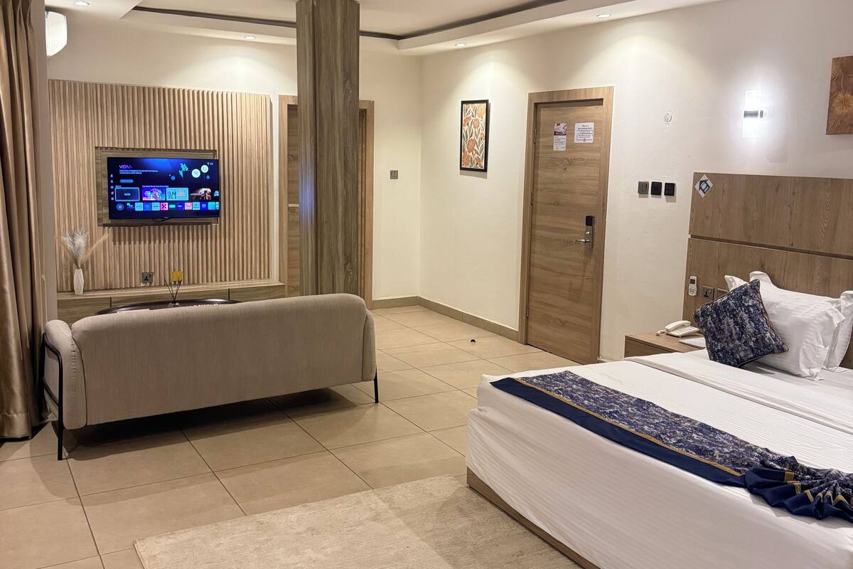 Een moderne hotelkamer met een groot bed, een slaapbank, een aan de muur bevestigde televisie en een houten accentmuur.