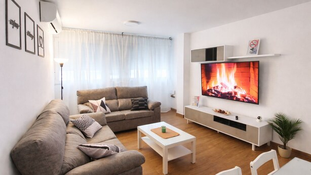 Ein modernes Wohnzimmer mit einer Couch, einem Couchtisch und einem Fernseher.