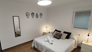 Ein Schlafzimmer mit einem Bett, einem Nachttisch, einem Spiegel und Wandbildern.
