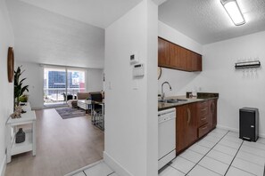 A modern apartment with a kitchen, dining area, and a view of the city.