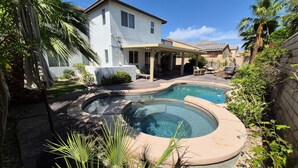 A residential backyard with a swimming pool, a covered patio, and a house. - Indio Oasis -Pool, Spa, Games & Outdoor Fun (Indio)