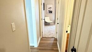 A hallway with wooden flooring, white walls, and doors leading to other rooms. - A Getaway on the Gulf Coast for the whole family! (Gulfport)