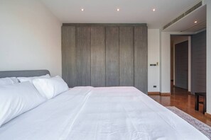 A bedroom with a large bed, a wooden headboard, and a built-in wardrobe. - Monochrome designer pool Villa (Bangkok)