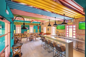 Zona de bar con barra, taburetes y decoración temática deportiva.