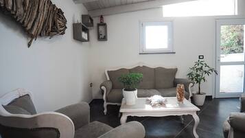 A living room with a grey sofa, a white coffee table, and two potted plants.