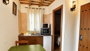 A compact kitchen with a microwave, sink, and a dining area with a table and chairs.