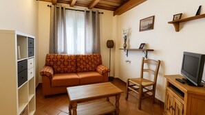 A cozy living room with a sofa, a wooden table, a TV, and a bookshelf.