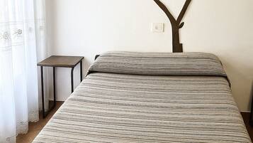 Un dormitorio con cama, una mesita y un adorno en la pared.