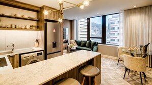 A modern kitchen with a marble countertop, a built-in washing machine, and a dining area with a glass table and chairs. - Trendy 1bed Modern Apt Cape Town City Suite 1601 (Cape Town)