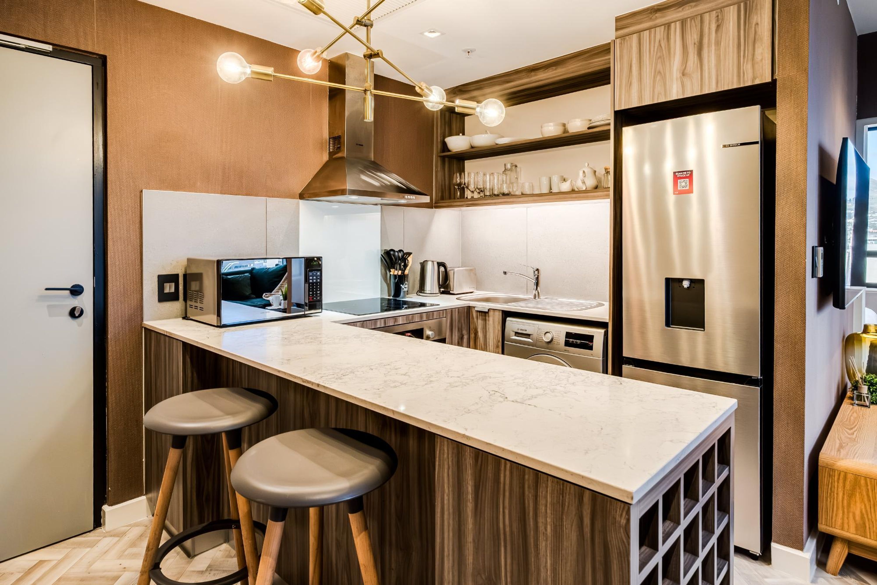 Una cocina moderna con encimera de mármol, electrodomésticos de acero inoxidable, detalles de madera y horno empotrado.