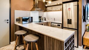 A modern kitchen with a marble countertop, stainless steel appliances, wooden accents, and a built-in oven. - Trendy 1bed Modern Apt Cape Town City Suite 1601 (Cape Town)