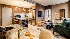 A modern apartment with a kitchen, dining area, and living room. It includes a dining table with chairs, a sofa, and a TV mounted on the wall. - Trendy 1bed Modern Apt Cape Town City Suite 1601 (Cape Town)