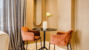 A room with a round table, two chairs, a vase with a flower, a mirror, and a curtain. - Mountain View Cape Town Apt City Suite 1614 (Cape Town)