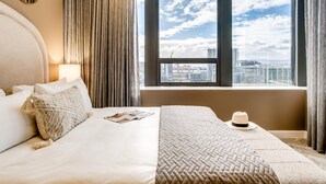 A hotel room with a large bed, a window with a city view, a lamp, and a hat on the bed. - Mountain View Cape Town Apt City Suite 1614 (Cape Town)