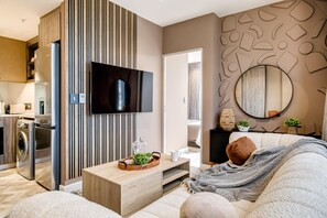 Un soggiorno moderno con una televisione a schermo piatto, un mobile basso in legno, un divano e un tavolino.