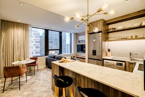 Une chambre d’hôtel moderne dotée d’une grande fenêtre, d’un coin repas, d’une cuisine et d’un bar.