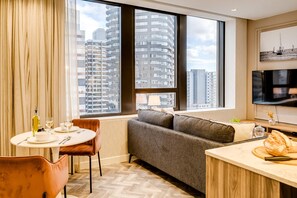 Une chambre d’hôtel moderne équipée d’un canapé, d’une table à manger et d’un téléviseur.