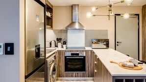 A modern kitchen with stainless steel appliances, a built-in oven, and a marble countertop. - 1bed Apt in Cape Town CBD City Suite 1602 (Cape Town)