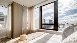 A hotel room with a large window, a bed with a decorative headboard, and a view of the cityscape. - 1bed Apt in Cape Town CBD City Suite 1602 (Cape Town)