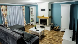 Een woonkamer met een bank, een salontafel, een open haard en een televisie.