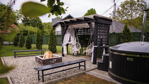 Een terras met een jacuzzi, zitplaatsen en een vuurkorf.
