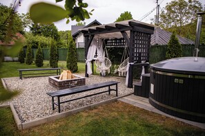 Un patio con jacuzzi, asientos y una chimenea.
