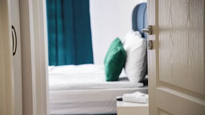 Een hotelkamer met een bed, nachtkastje en een deur.