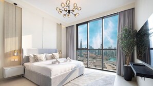 Un dormitorio moderno con una cama grande, vistas de la ciudad, una planta en maceta y un televisor en la pared.