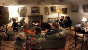 A cozy living room with a fireplace, comfortable seating, and a Christmas tree.