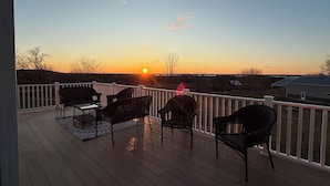 A deck with outdoor furniture and a view of the sunset.
