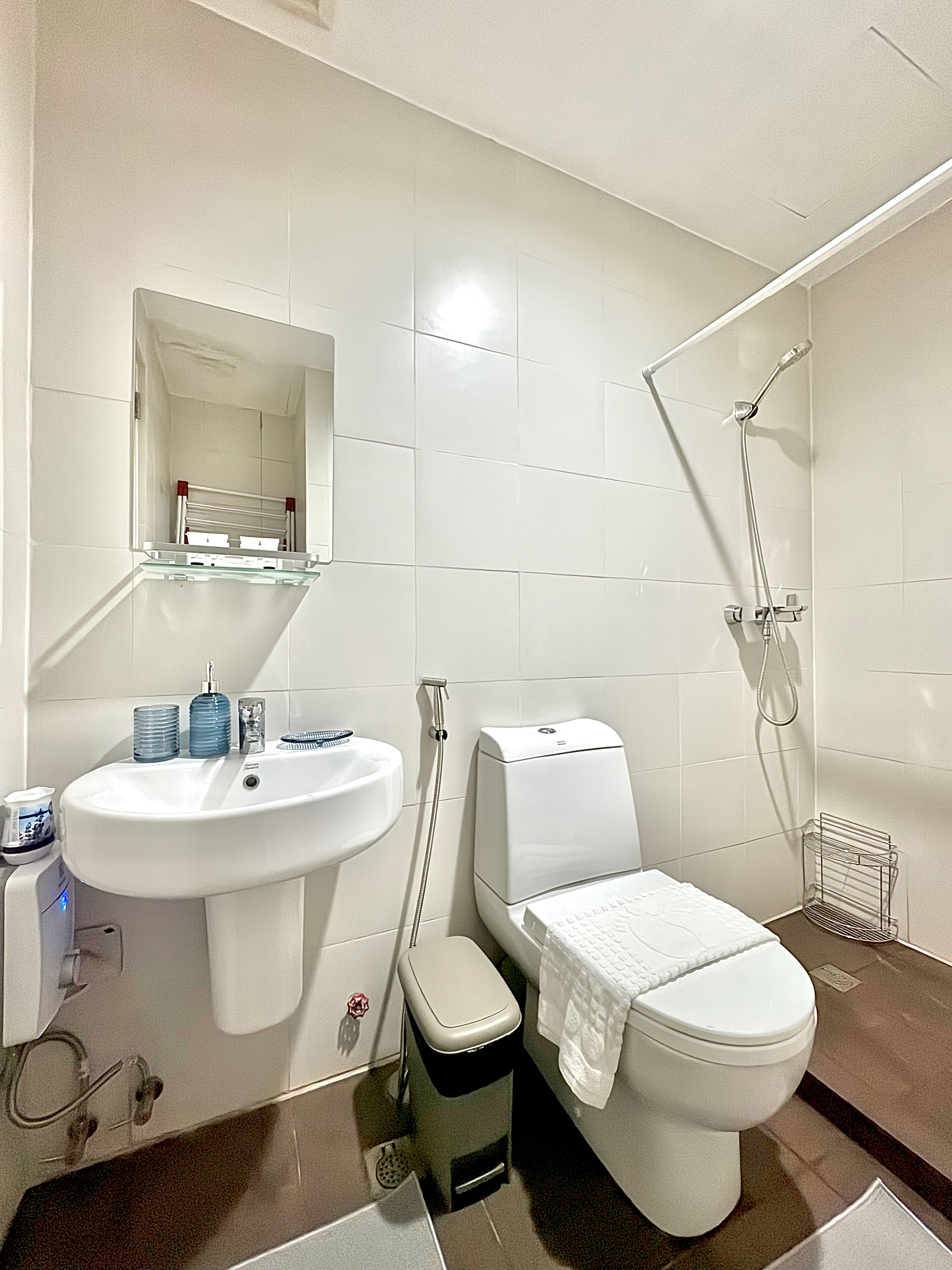 A modern bathroom with a white sink, mirror, toilet, and shower.