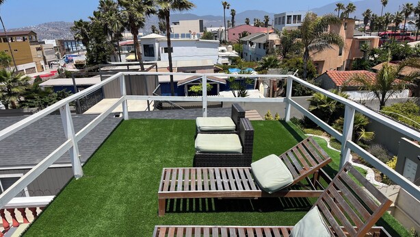 A rooftop patio with artificial grass, two wooden lounge chairs, and a white railing. - 2 Bedroom Suite in beautiful Ensenada with a jacuzzi in the room. Ocean view! (Ensenada)