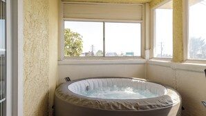 A hot tub in a corner with a window view of a cityscape. - 2 Bedroom Suite in beautiful Ensenada with a jacuzzi in the room. Ocean view! (Ensenada)