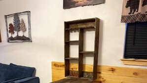 A rustic wooden bench with a shelf, a blue sofa, and a wooden wall panel. - Bear Cabin (Noble)